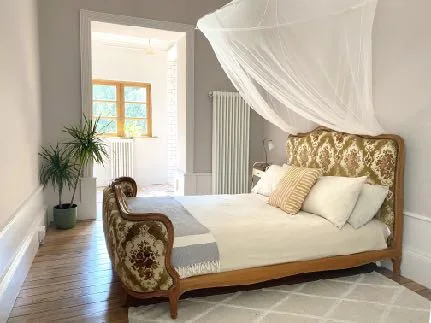 A bright bedroom in the main house with wooden floors and a canopy bed