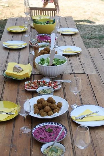 A long outdoor table laid with fresh vegetarian dishes