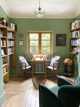 The library, with bookshelves, armchairs and garden views