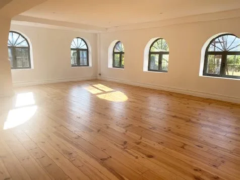 The wooden-floored studio with tall arched windows